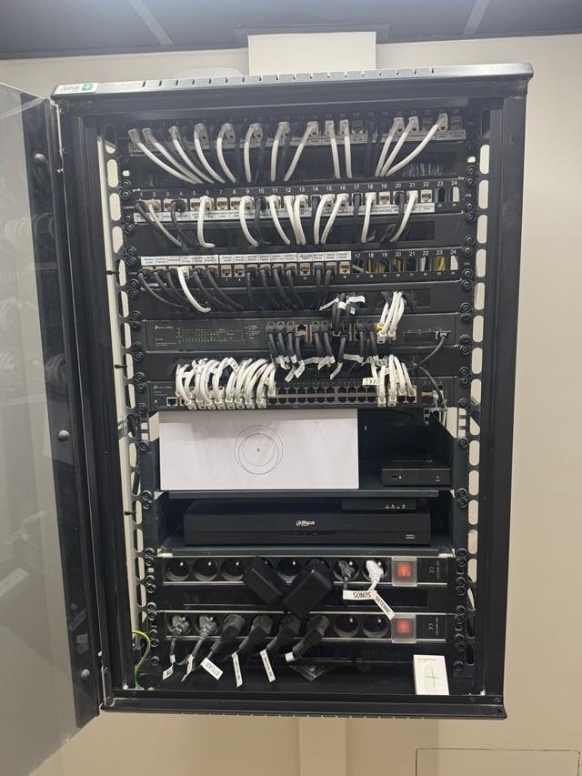 Baie de brassage de villa avec trois panneaux RJ45 repérés, switchs et enregistreur vidéo