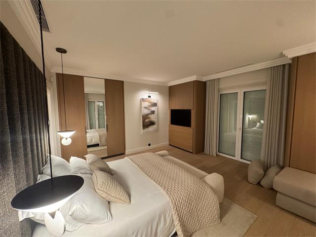 Chambre avec suspensions de chevet, applique de tableau et téléviseur intégré au meuble en chêne