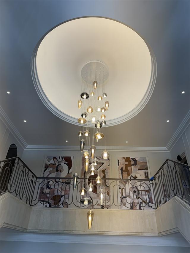 Grande suspension de globes en verre dans une cage d'escalier avec coupole éclairée et spots encastrés