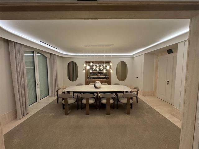 Salle à manger avec gorge lumineuse LED au plafond et suspension de globes en verre au-dessus de la table